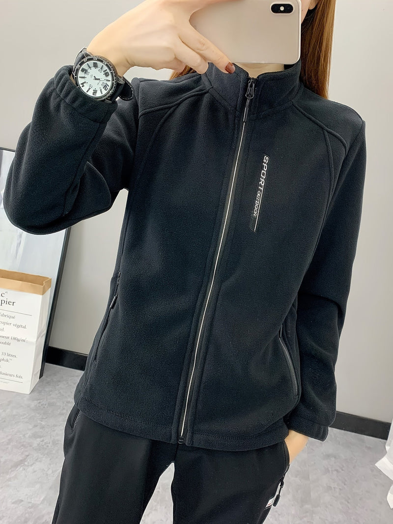 Frau in schwarzer Fleecejacke mit Reißverschluss, Sportuhr, Smartphone, Indoor-Hintergrund.