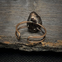 Antiker Bronze-Ring mit schwarzem Edelstein auf rustikalem Holzuntergrund.