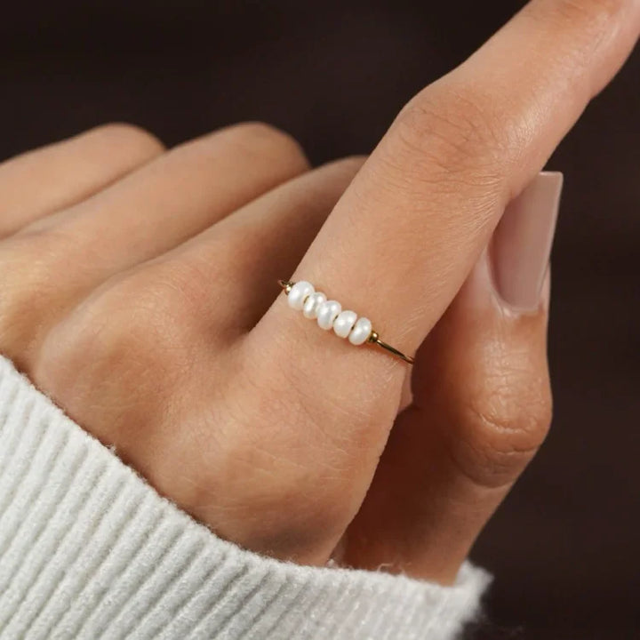 Dünner Goldring mit kleinen weißen Perlen, eleganter Schmuck, Damenmode, Nahaufnahme.