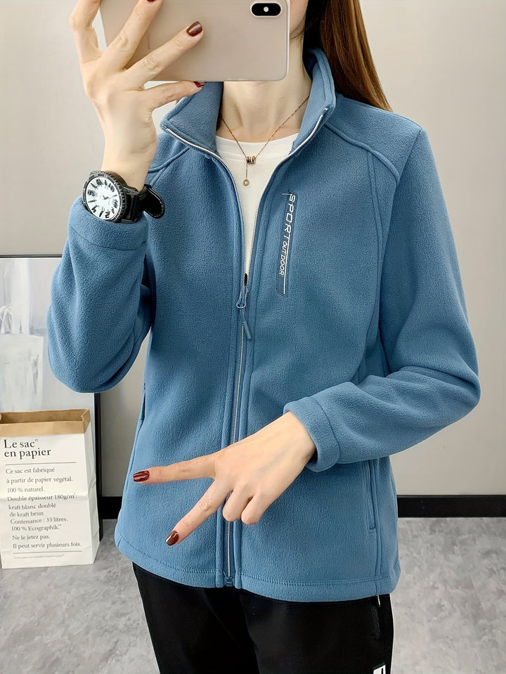 Frau in blauer Fleecejacke mit Reißverschluss, Sportuhr, Smartphone, lässiger Look.