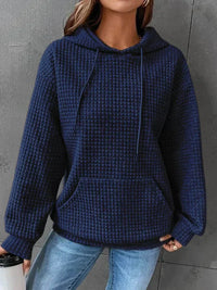 Frau in blauem Kapuzenpullover aus Strickstoff, lässig, modisch, Herbstmode, Jeans.