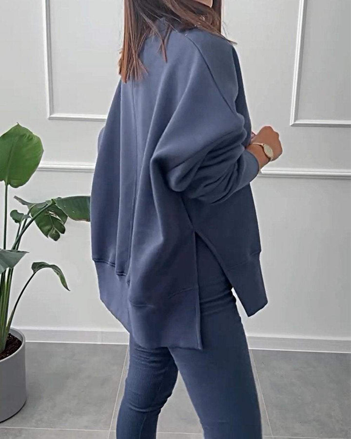 Frau in dunkelblauem Oversize-Sweatshirt und Leggings, moderne Freizeitmode, Zimmerpflanze.