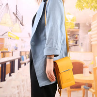 Damenmode: Hellblauer Blazer, gelbe Ledertasche, stilvoll, modern, urbaner Hintergrund.