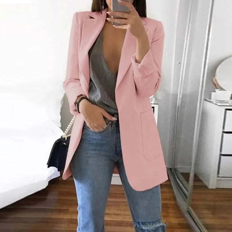 Dame im rosa Blazer, grauem Top und Jeans, modisch, Spiegel-Selfie, moderne Kleidung.