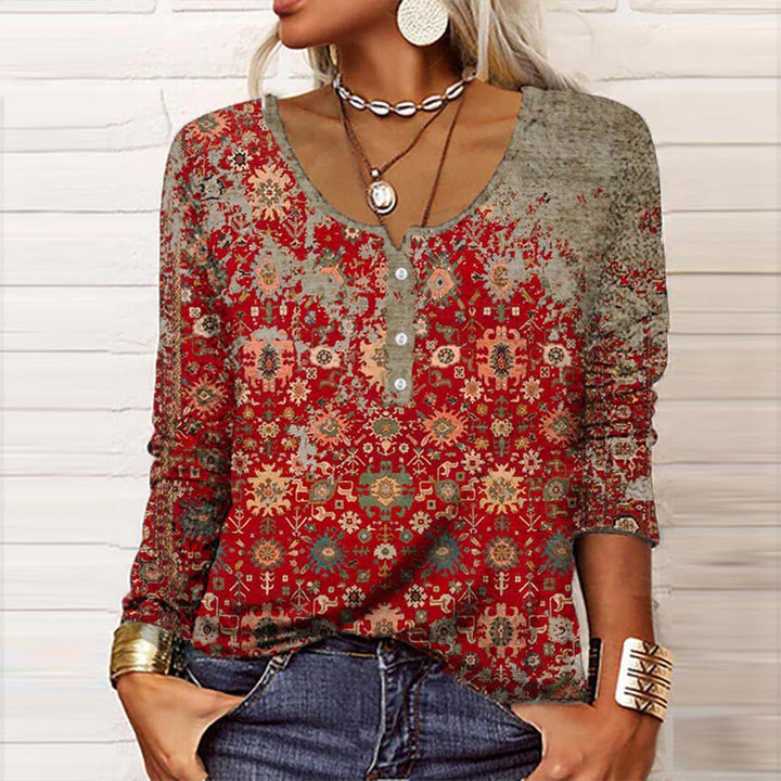 Frau in rotem, gemustertem Langarmshirt, Jeans, Schmuck, modisch, lässig, Boho-Stil.