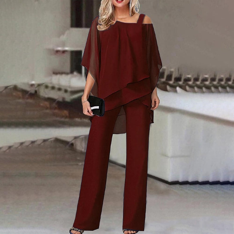 Frau in eleganter, weinroter Chiffon-Hose und Bluse, Abendmode, schulterfrei, mit Clutch.
