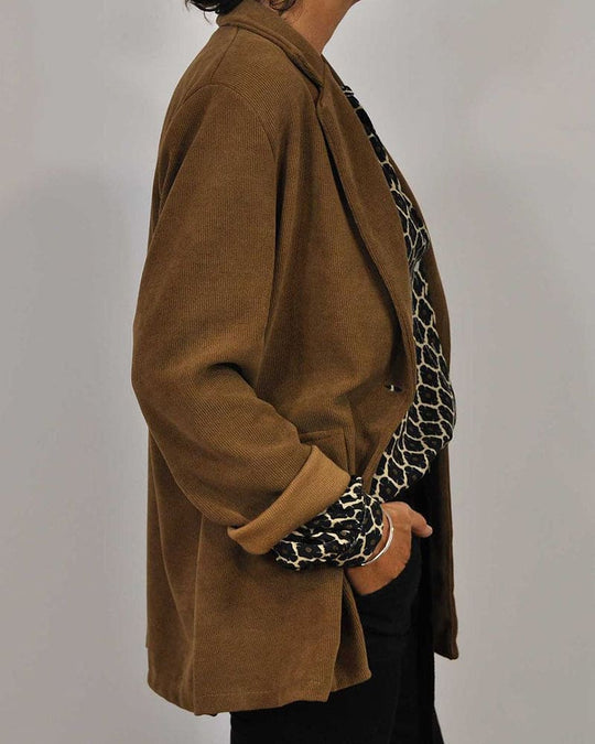 Brauner Damenblazer aus Baumwolle, lässig geschnitten, kombiniert mit gemustertem Oberteil.