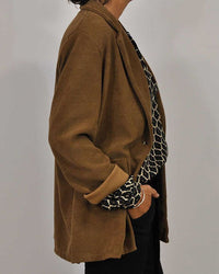 Brauner Damenblazer aus Baumwolle, lässig geschnitten, kombiniert mit gemustertem Oberteil.