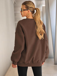 Frau in braunem Oversize-Pullover, blonde Haare, Sonnenbrille, modisch, lässiger Stil.