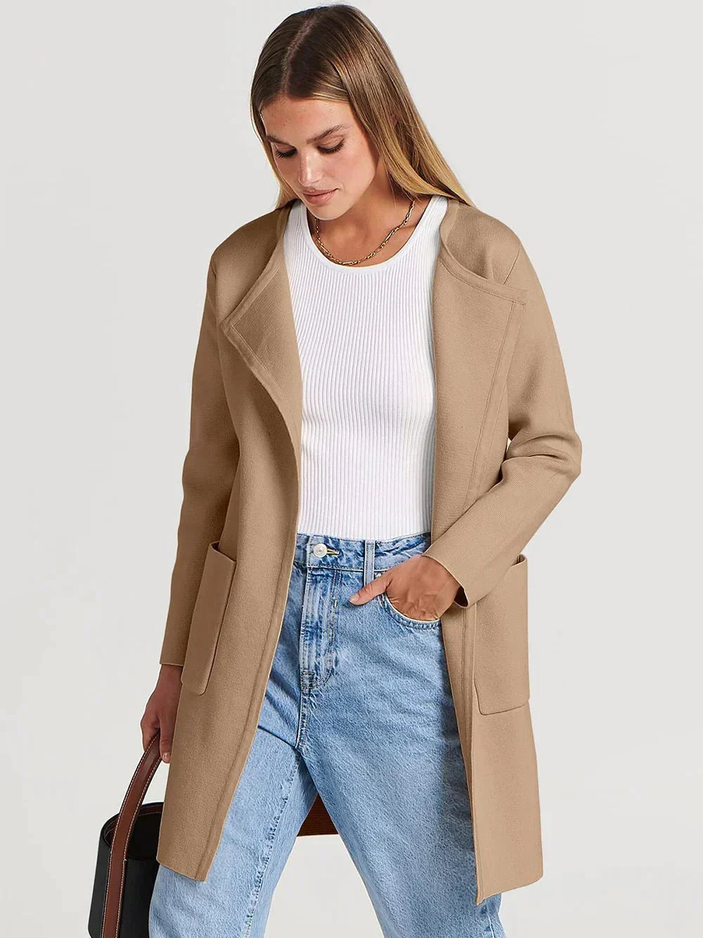 Frau trägt beige Damen-Cardigan, weißes Oberteil, blaue Jeans, modischer Look.