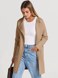 Frau trägt beige Damen-Cardigan, weißes Oberteil, blaue Jeans, modischer Look.