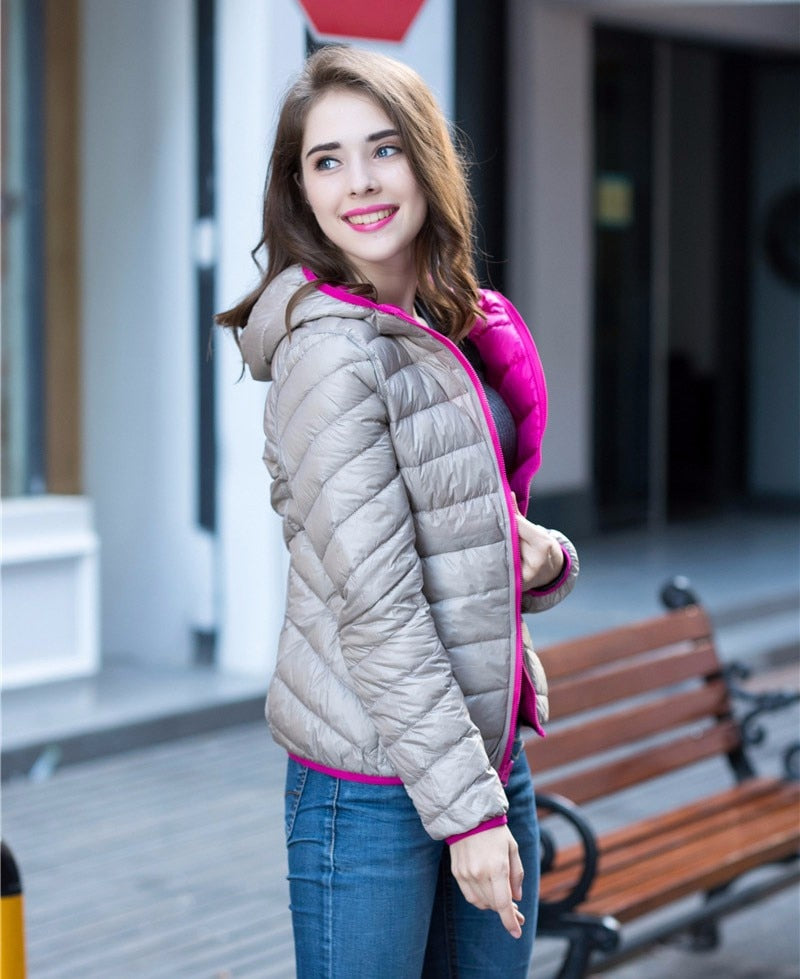 Frau in grauer Daunenjacke mit Kapuze, lächelnd, draußen, modisch, Herbstkleidung.