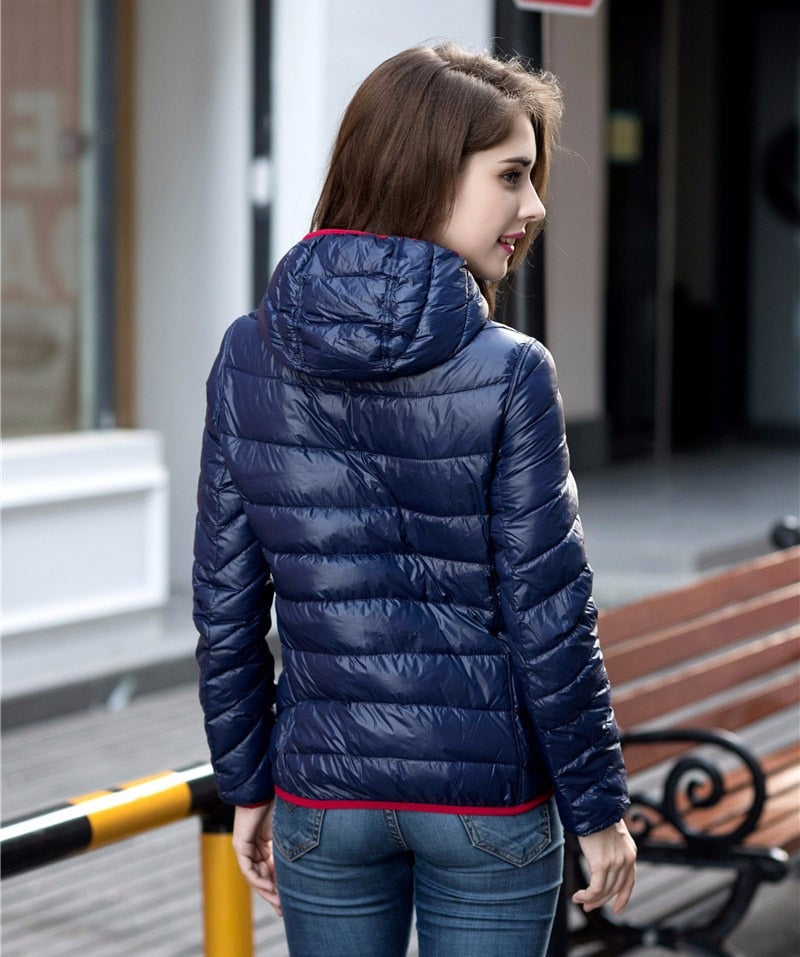 Frau in blauer Daunenjacke, Kapuze, Jeans, draußen, Herbstmode, stilvoll, warm, bequem.