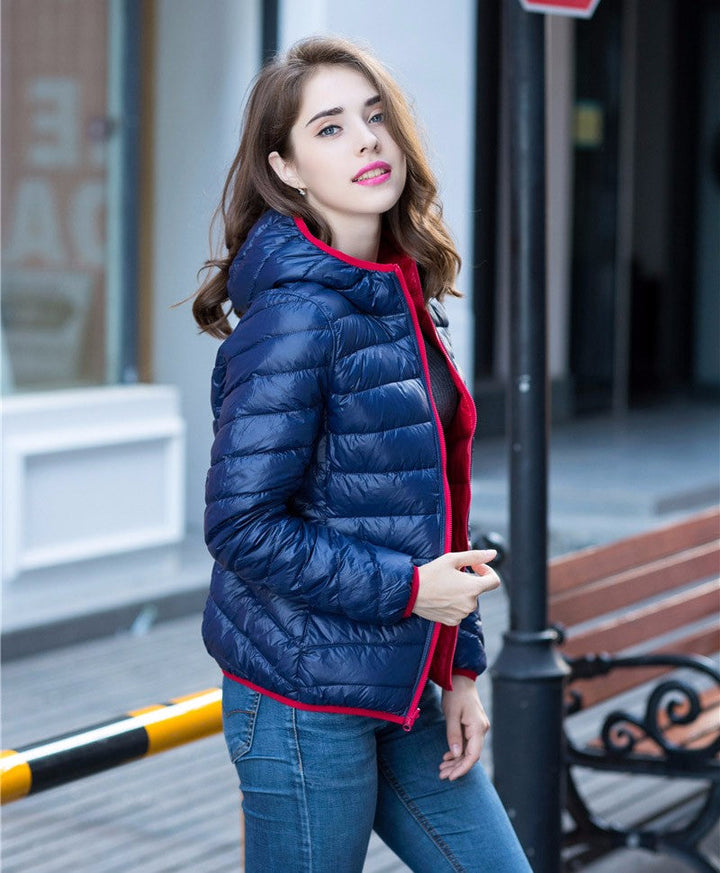 Frau in blauer Daunenjacke mit Kapuze, modisch, draußen, Herbstmode, lässiger Stil.