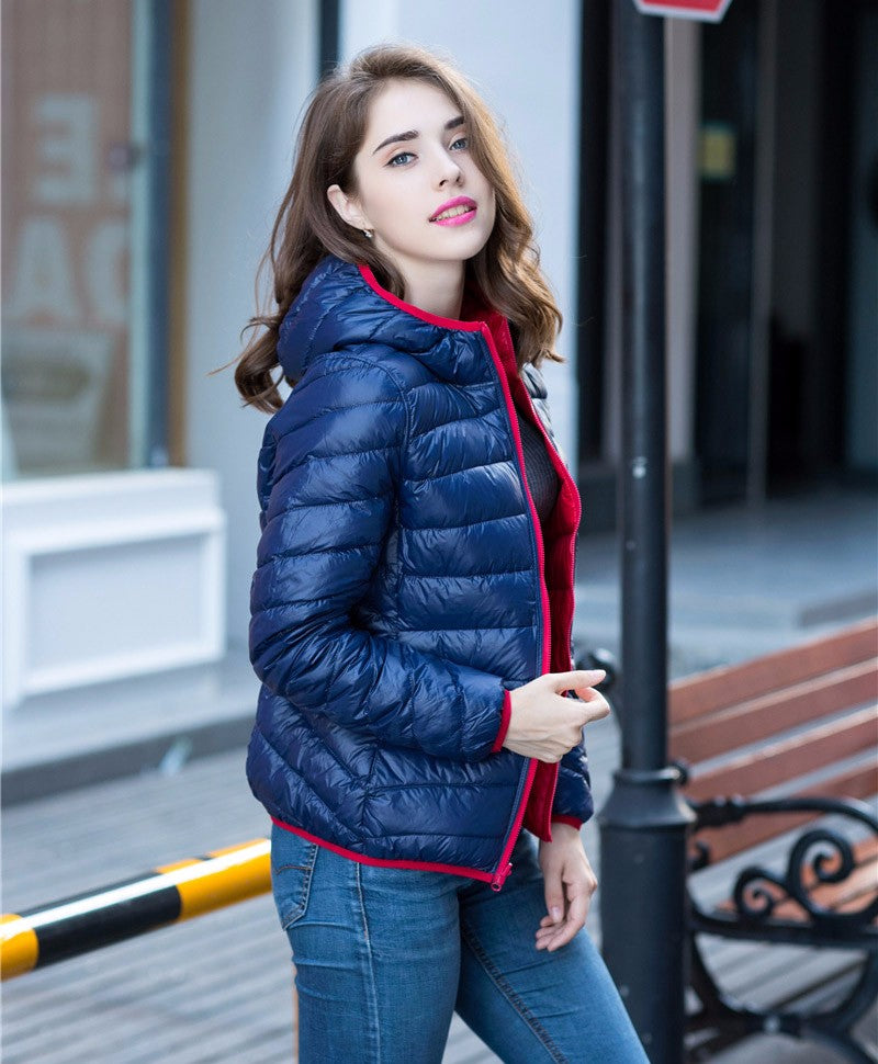 Frau in blauer Daunenjacke mit Kapuze, modisch, draußen, Herbstmode, lässiger Stil.