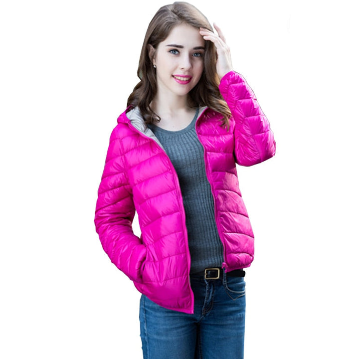 Frau in pinker Daunenjacke, grauem Pullover und blauer Jeans, lächelnd, modisch, Winterkleidung.