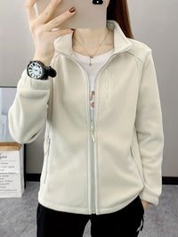 Frau in weißer Fleecejacke mit Reißverschluss, Smartphone, Armbanduhr, Innenraum.