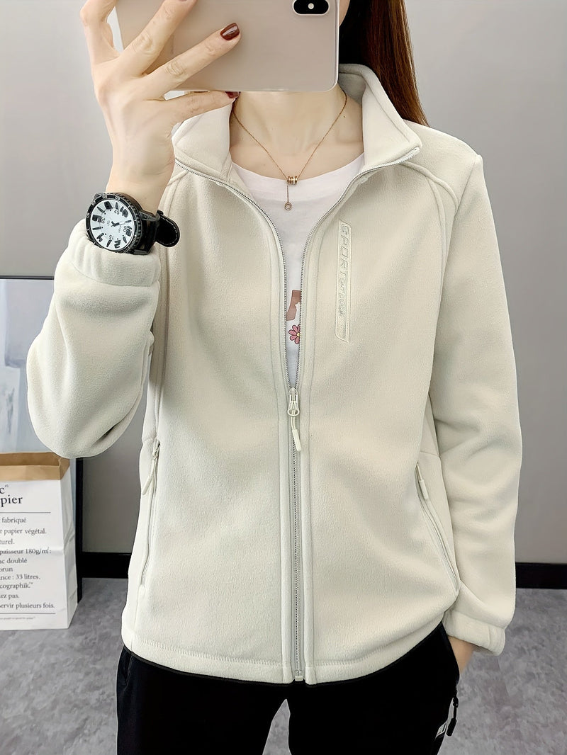 Frau in weißer Fleecejacke mit Reißverschluss, Smartphone, Armbanduhr, Innenraum.