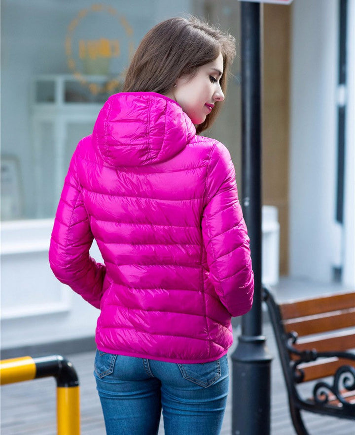 Frau in pinker Daunenjacke, Kapuze, draußen, modisch, Winterbekleidung, Rückansicht.