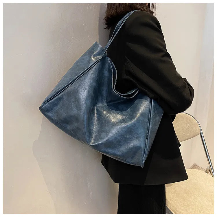Frau mit großer blauer Ledertasche, modisch, elegant, Damenaccessoire, Schultertasche.