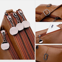 Braune Leder-Umhängetasche mit mehreren Reißverschlüssen und Smartphone-Fach.