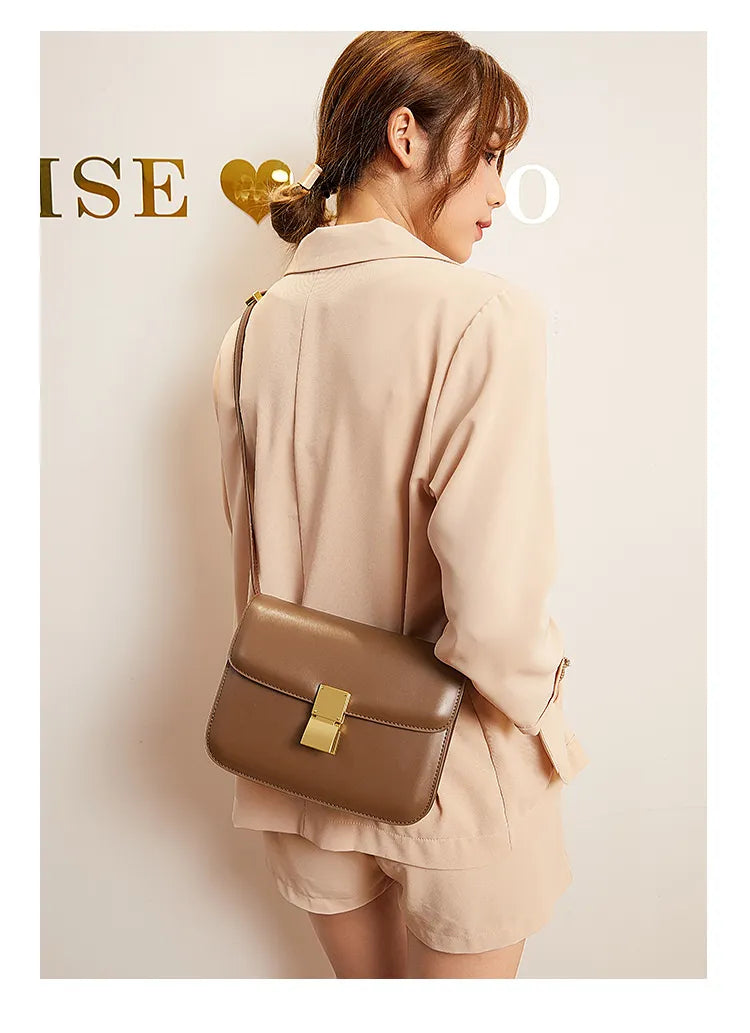 Frau mit brauner Ledertasche, goldener Verschluss, elegantes Design, Damenmode, beige Outfit.