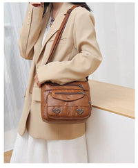 Frau mit brauner Leder-Umhängetasche, eleganter Blazer, modisches Accessoire, Damenmode.