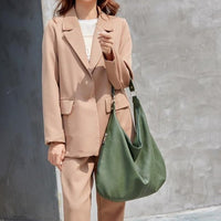 Frau mit beigem Blazer und grüner Ledertasche, modisches Outfit, elegante Damenmode.