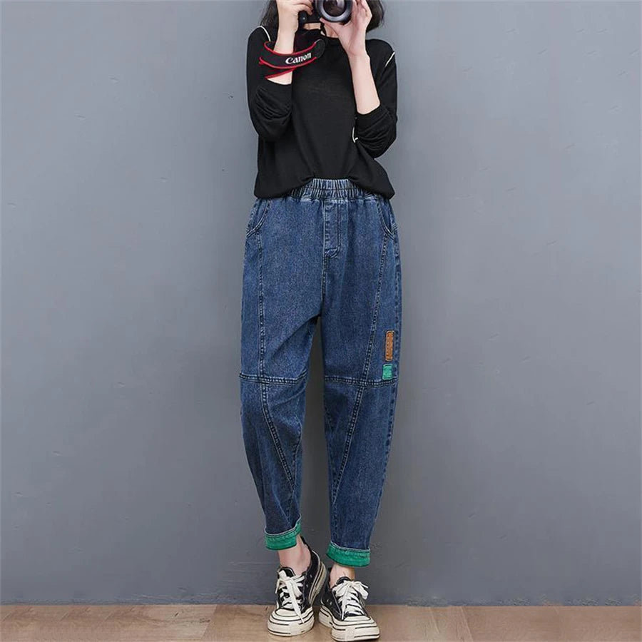 Frau in blauer Jeans und schwarzem Pullover fotografiert, lässiger Streetwear-Look.