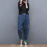 Frau in blauer Jeans und schwarzem Pullover fotografiert, lässiger Streetwear-Look.