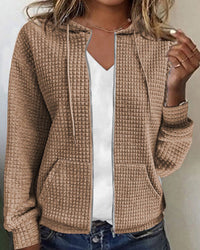Frau trägt beige Kapuzenjacke mit Waffelmuster, Reißverschluss, lässig, modisch, Herbstmode.