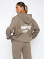 Frau in braunem Hoodie mit "White Fox" Aufdruck, Kapuze, lässiger Stil, Streetwear-Mode.