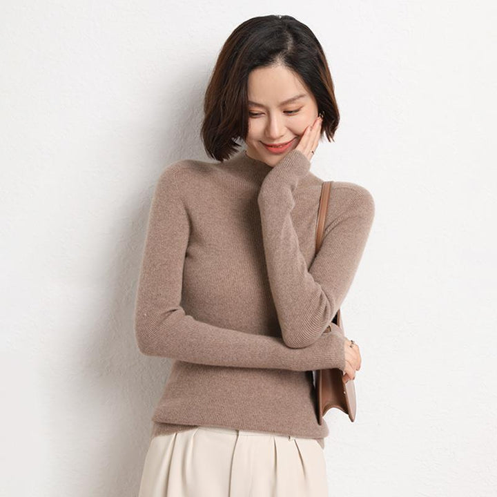 Frau in beigem Rollkragenpullover aus Kaschmir, lächelnd, mit brauner Handtasche.