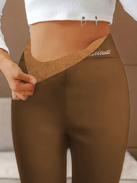 Frau in brauner Leggings mit hohem Bund und weißem Oberteil, zeigt elastischen Bund.