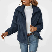 Frau in dunkelblauer Strickjacke, weißem Rollkragenpullover, Jeans; modische Winterkleidung.