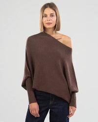 Frau trägt braunen, asymmetrischen Pullover aus Wolle, lässiger Stil, Herbstmode.