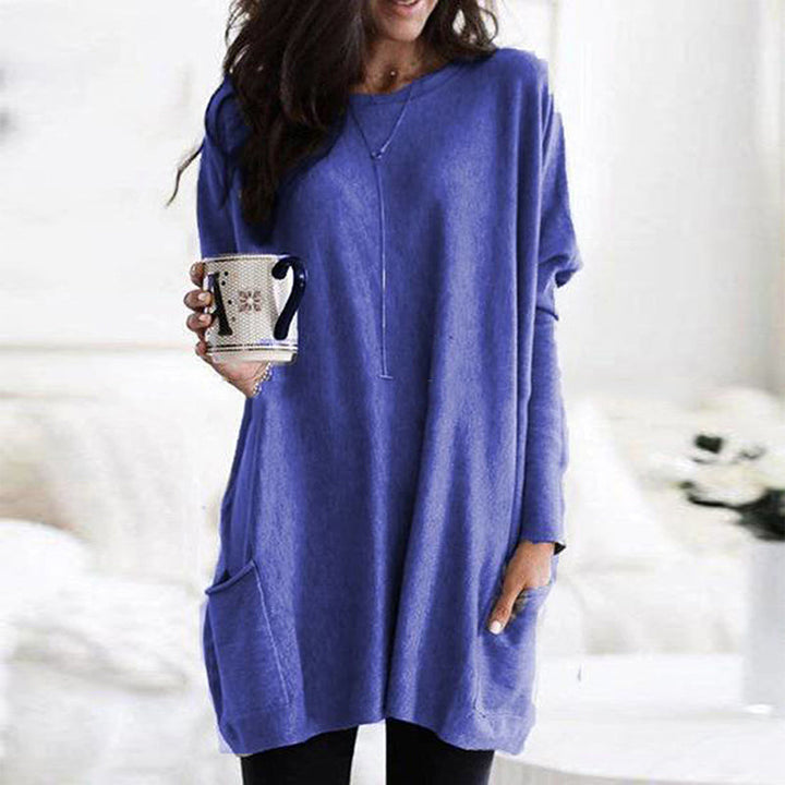 Frau in blauem Oversize-Pullover mit Kaffeetasse, gemütliche Wintermode, Wohnzimmer.