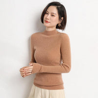 Frau in braunem Kaschmirpullover, lächelnd, vor weißer Wand. Elegante Damenmode.