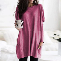 Frau in rosa Oversize-Pullover mit Kaffeetasse, gemütliche Herbstmode, Wohnzimmer.