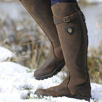 Braune Lederreitstiefel im Schnee, wasserdicht, robust, ideal für Outdoor-Aktivitäten.