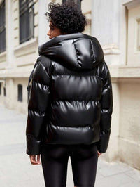 Frau in schwarzer, glänzender Daunenjacke auf städtischer Straße, Wintermode, Outdoor-Bekleidung.