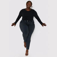 Frau in schwarzem Langarmshirt und dunkler Jeans, lächelnd, Plus-Size-Mode, Studioaufnahme.