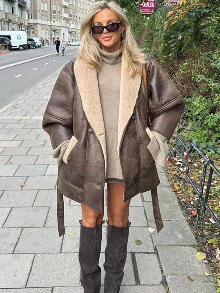 Frau in brauner Lederjacke mit Schaffell, beiger Rollkragenpullover, schwarze Stiefel, Straße.
