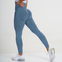 Frau in blauer Sportleggings, nahtlos, hohe Taille, beim Dehnen, weiße Turnschuhe.