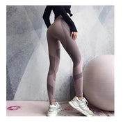 Frau in rosa Sportleggings und Sneakers neben Gymnastikball vor grauer Wand.
