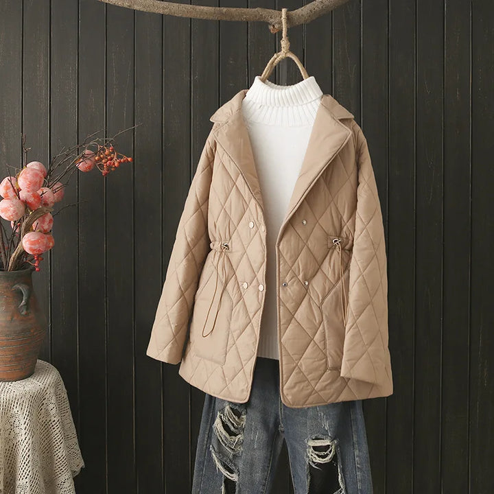 Beige gesteppte Damenjacke, Herbstmode, mit Kordelzug, über weißem Rollkragenpullover.