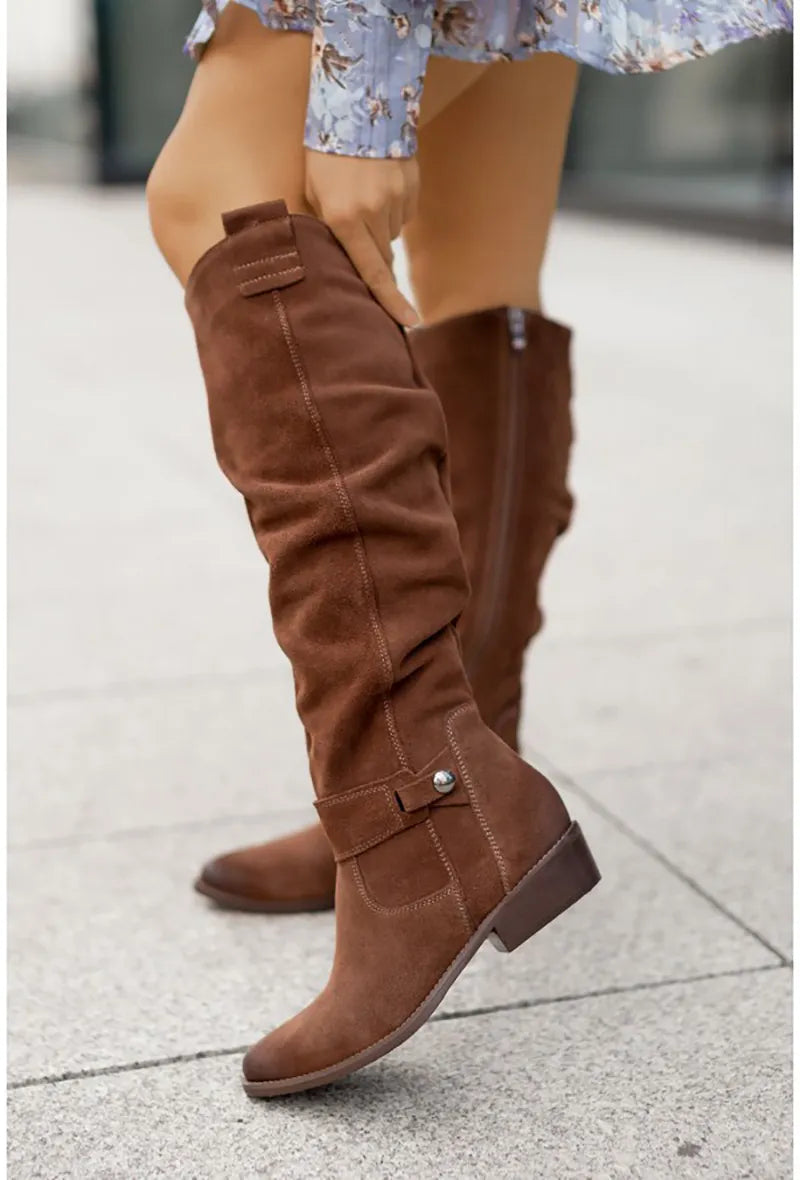 Braune Wildleder-Stiefel für Damen, kniehoch, modisch, Herbstmode, Straßenhintergrund.