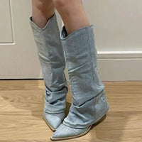 Damen Stiefel aus hellblauem Denim, spitz zulaufend, kniehoch, modisch, auf Holzboden.