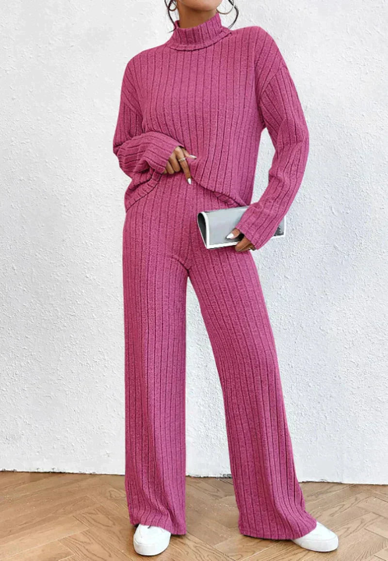 Frau in rosa Strickpullover und Hose, hält silberne Clutch, modisch, bequem, Herbstmode.