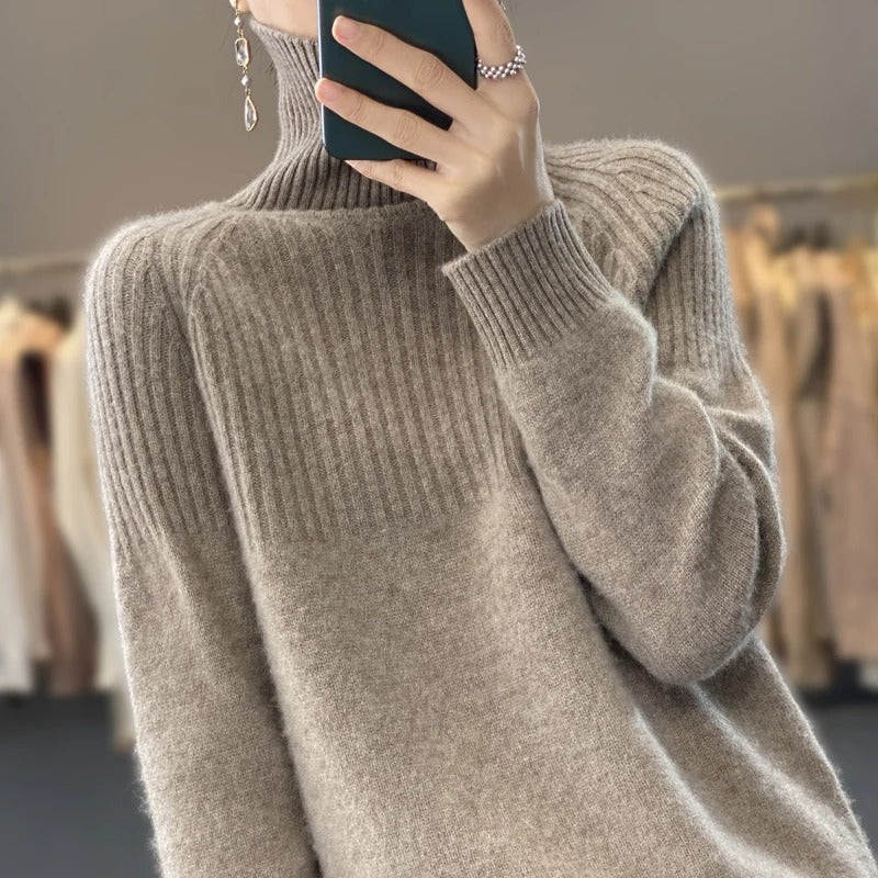 Frau in beigem Strickpullover mit hohem Kragen, hält Smartphone, modisches Herbstoutfit.